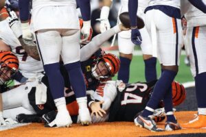 Cincinnati Bengals quarterback Joe Burrow reaching for a touchdown under a pile of defenders.