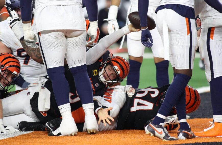 Cincinnati Bengals quarterback Joe Burrow reaching for a touchdown under a pile of defenders.