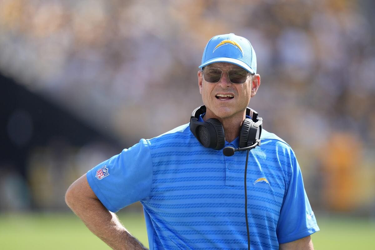 Los Angeles Charger Coach Jim Harbaugh wearing a Chargers hat and black sunglasses with a headset around his neck.