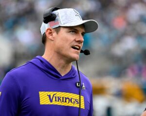 Minnesota Vikings head coach Kevin O'Connell speaks into a headset.