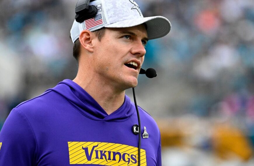 Minnesota Vikings head coach Kevin O'Connell speaks into a headset.