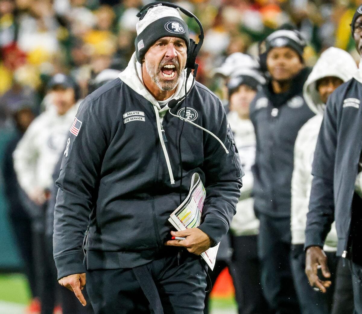 San Francisco 49ers head coach yelling on the sideline of a football game.