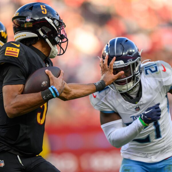 Washington Commanders quarterback Jayden Daniels stiff-arms a defender.