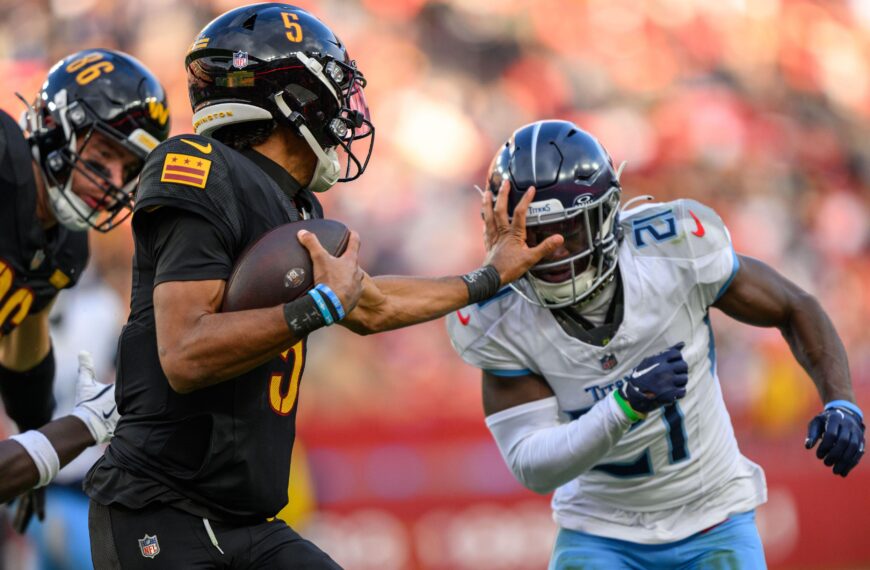 Washington Commanders quarterback Jayden Daniels stiff-arms a defender.