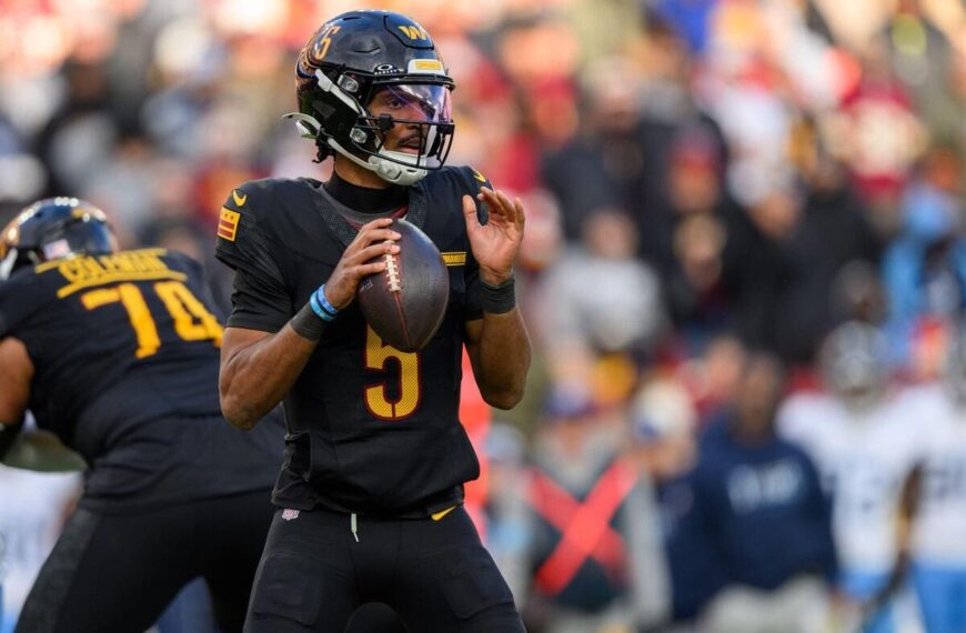 Washington Commanders quarterback Jayden Daniels holding a football during a play.