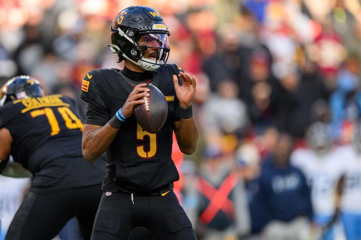 Washington Commanders quarterback Jayden Daniels holding a football during a play.