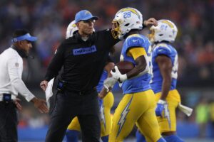 Los Angeles Chargers head coach Jim Harbaugh celebrates with running back Hassan Haskins.