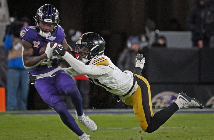 Baltimore Ravens wide receiver Zay Flowers being tackled by a member of the Pittsburgh Steelers while catching a pass.