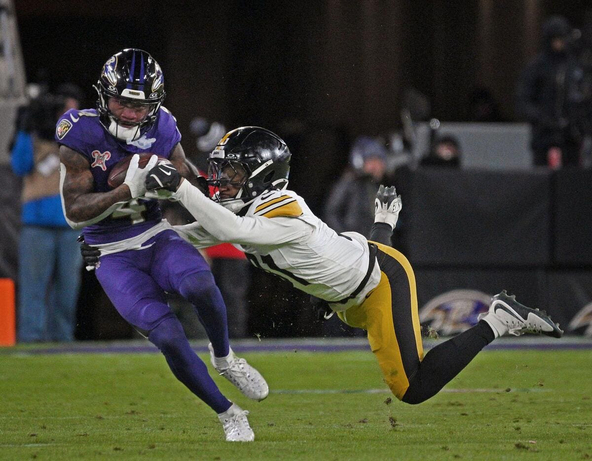 Baltimore Ravens wide receiver Zay Flowers being tackled by a member of the Pittsburgh Steelers while catching a pass.