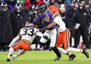 Baltimore Ravens running back Derrick Henry being tackled by two members of the Cleveland Browns.