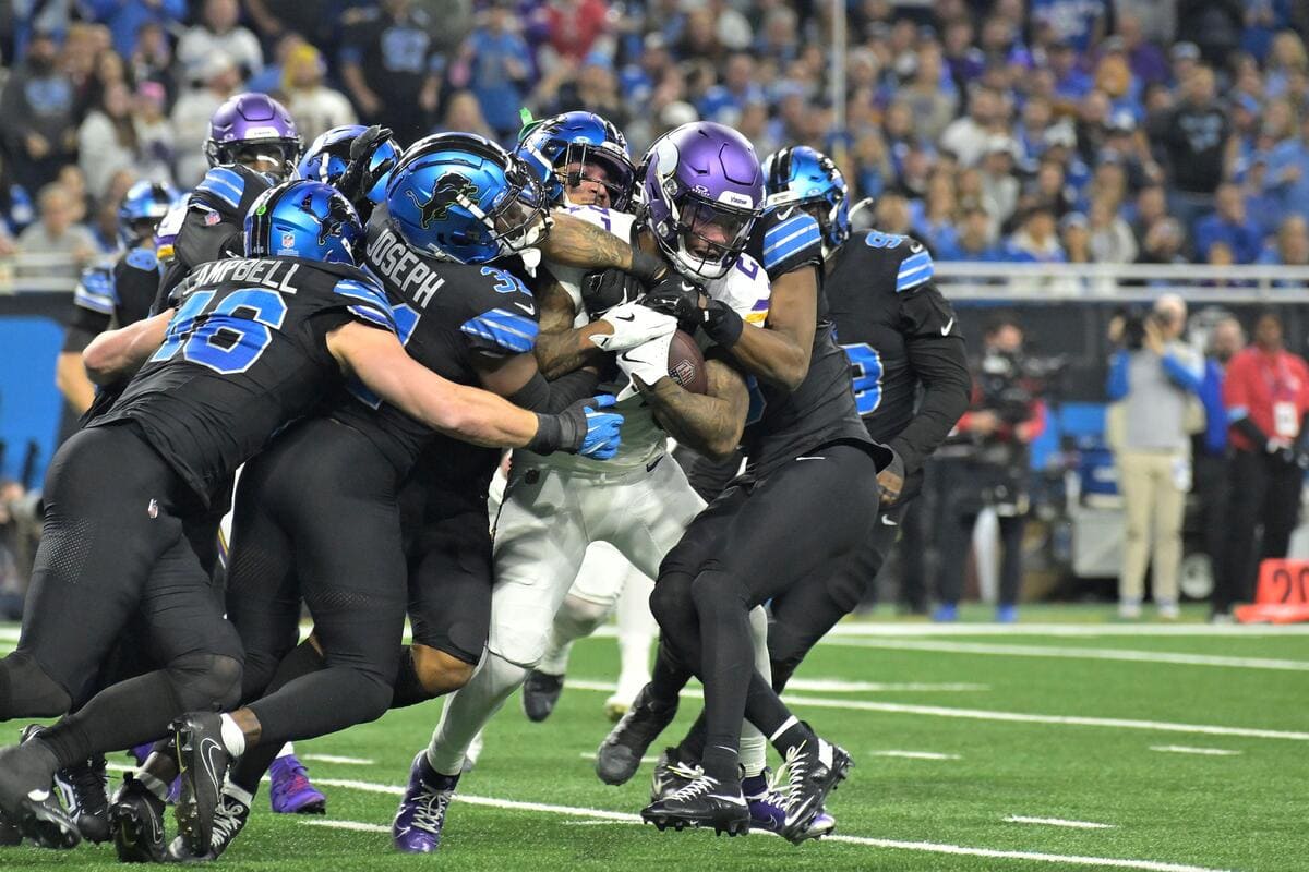 Minnesota Vikings running back Cam Akers is tackled by five members of the Detroit Lions defense.