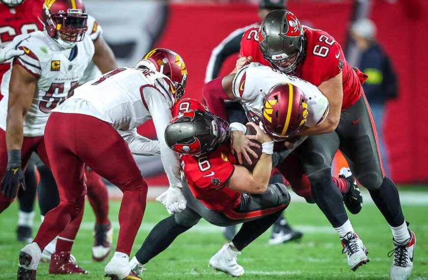 Tampa Bay Buccaneers quarterback Baker Mayfield is tackled down by Washington Commanders defenders.