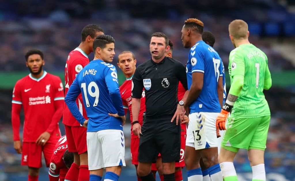 LIVERPOOL, ENGLAND - OCTOBER 17: Players of both teams surround Match Referee, Michael Oliver during the Premier League match between Everton and Liverpool at Goodison Park on October 17, 2020 in Liverpool, England. Sporting stadiums around the UK remain under strict restrictions due to the Coronavirus Pandemic as Government social distancing laws prohibit fans inside venues resulting in games being played behind closed doors. (Photo by Catherine Ivill/Getty Images)